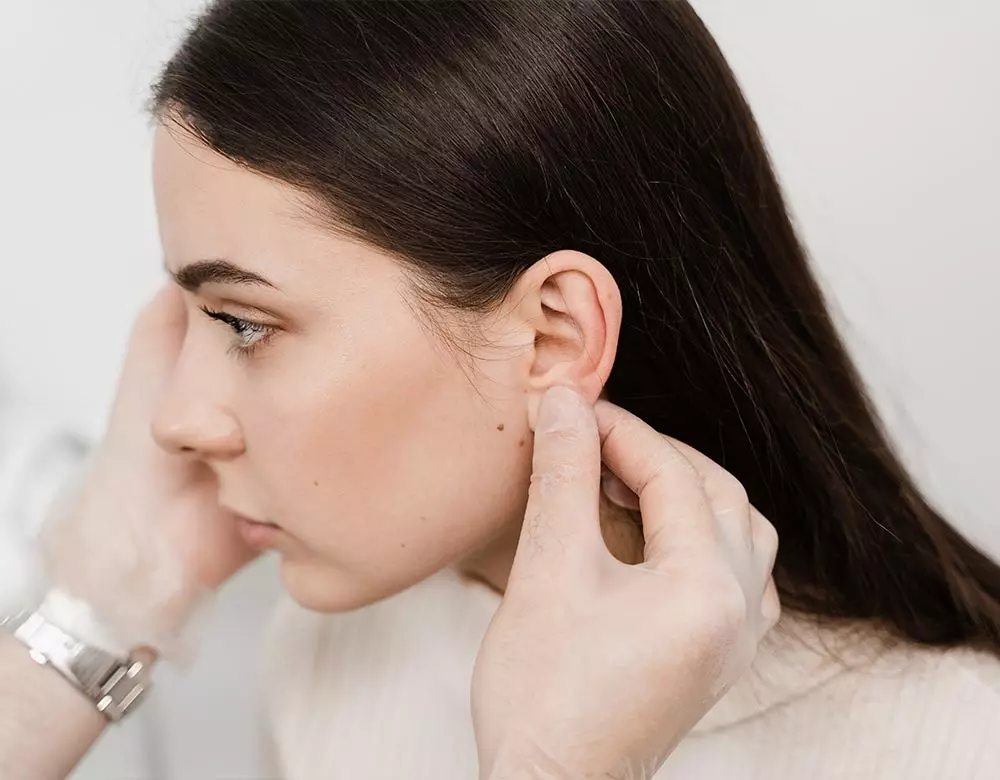 Eine Patientin die eine Ohrenkorrektur beim Hautarzt machen lässt